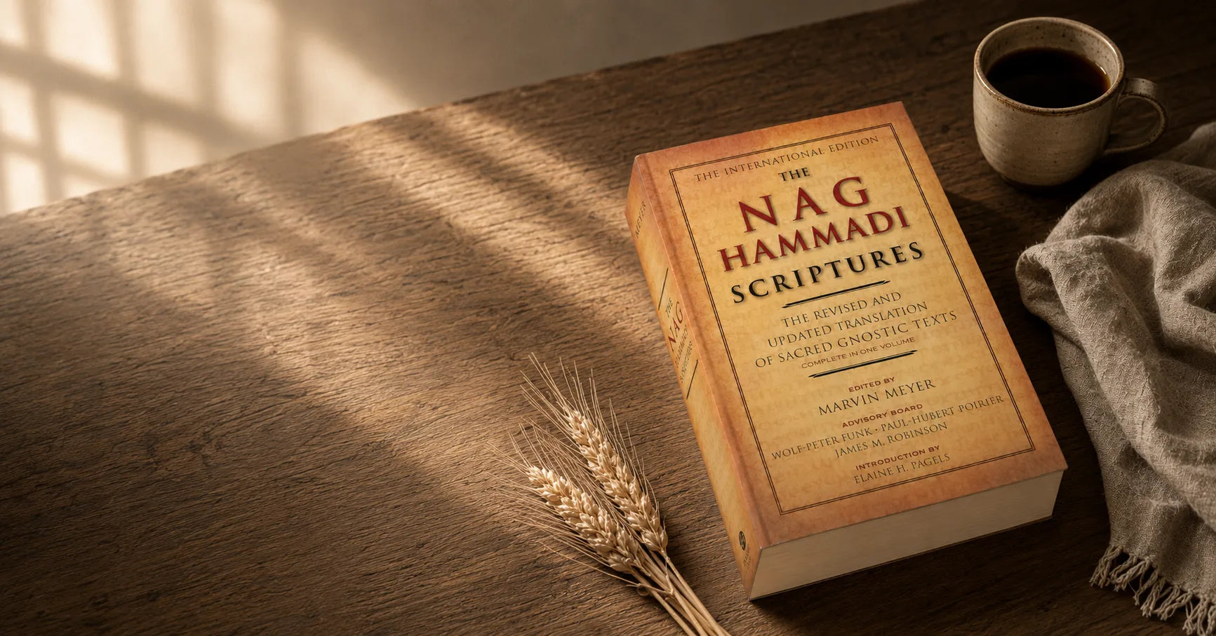 The paperback on a sunlit wooden table beside wheat stems and a cup of coffee