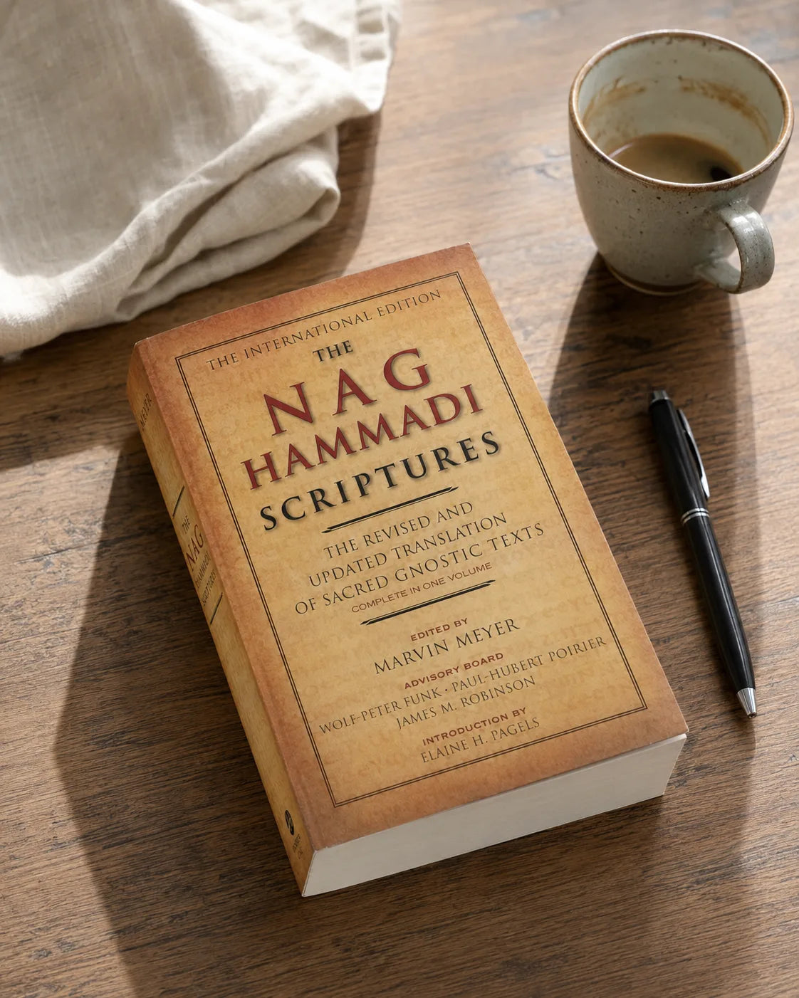 The paperback on a warm reading table beside a mug and pen