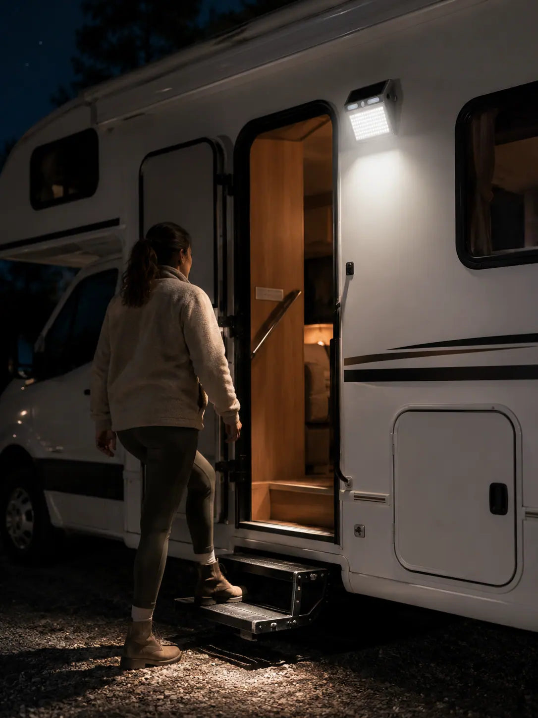 The light switching on as a woman steps up to the RV door at night
